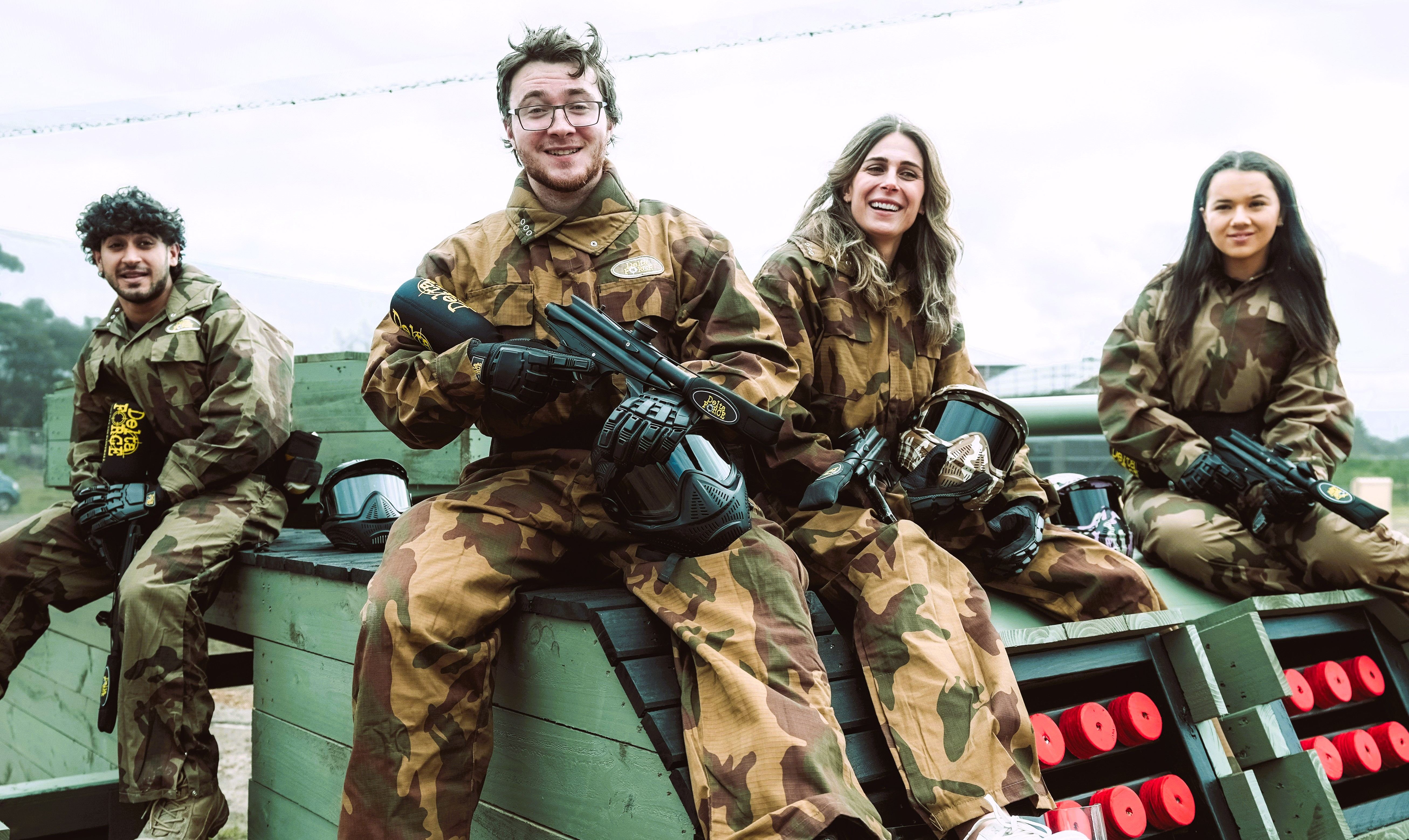 Friends smiling in paintball kit on a sunny day
