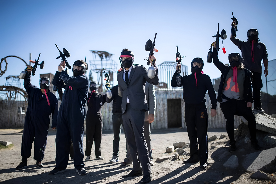 Corporate paintball group celebrating with paintball markers raised