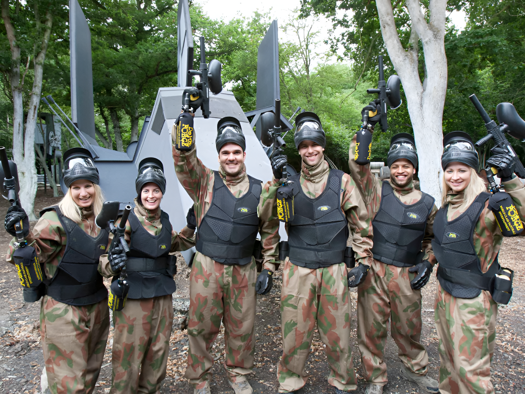 Corporate paintball team smiling in front of a game zone prop