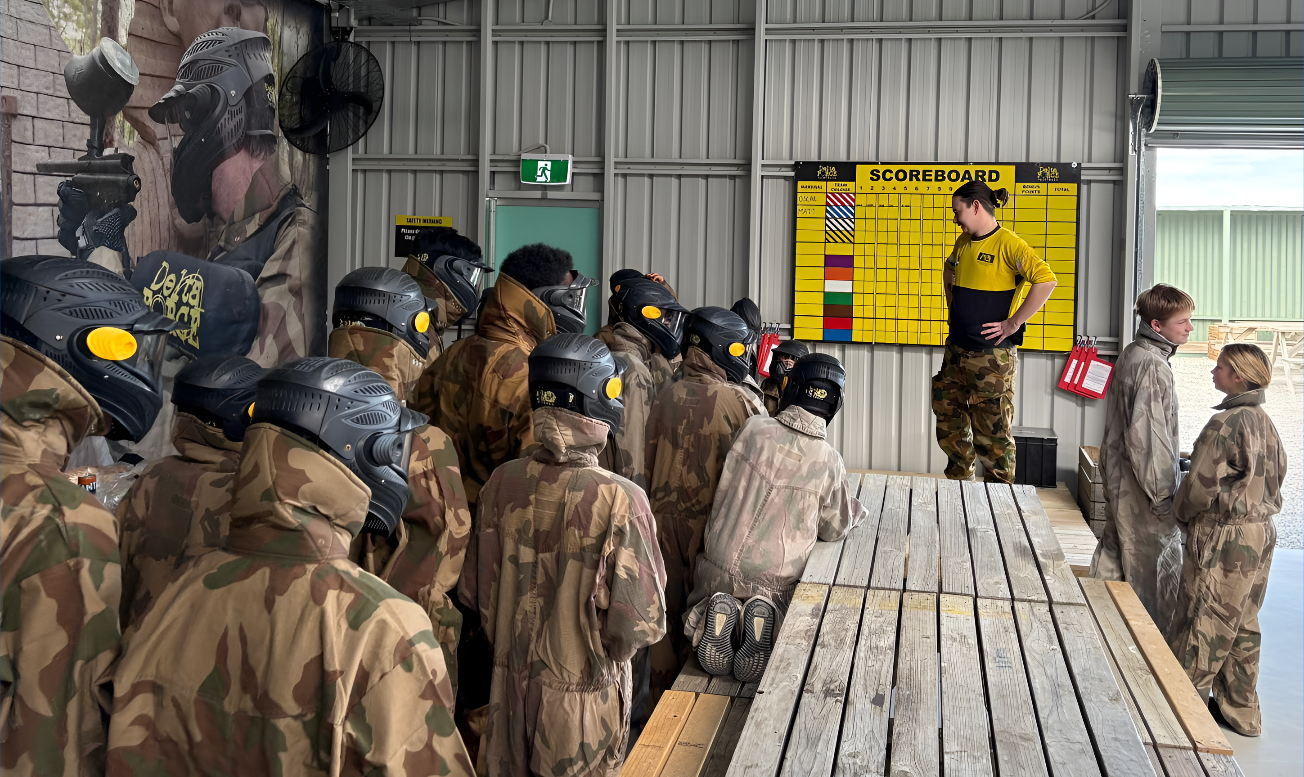 Kids paintball briefing beside a scoreboard