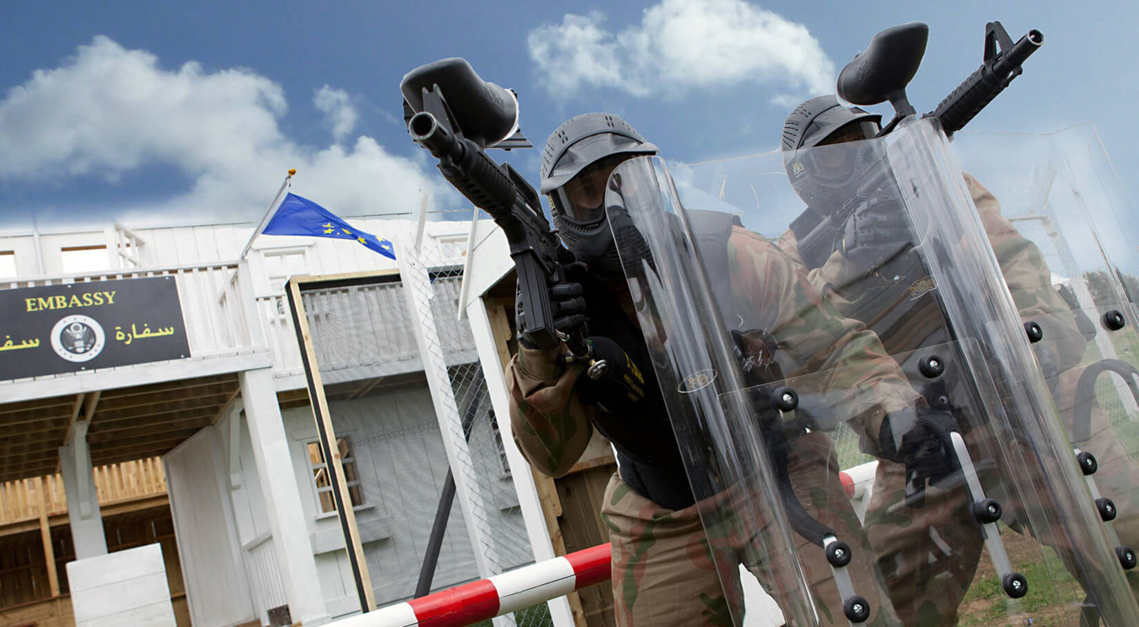 Paintball players moving forward behind a protective shield