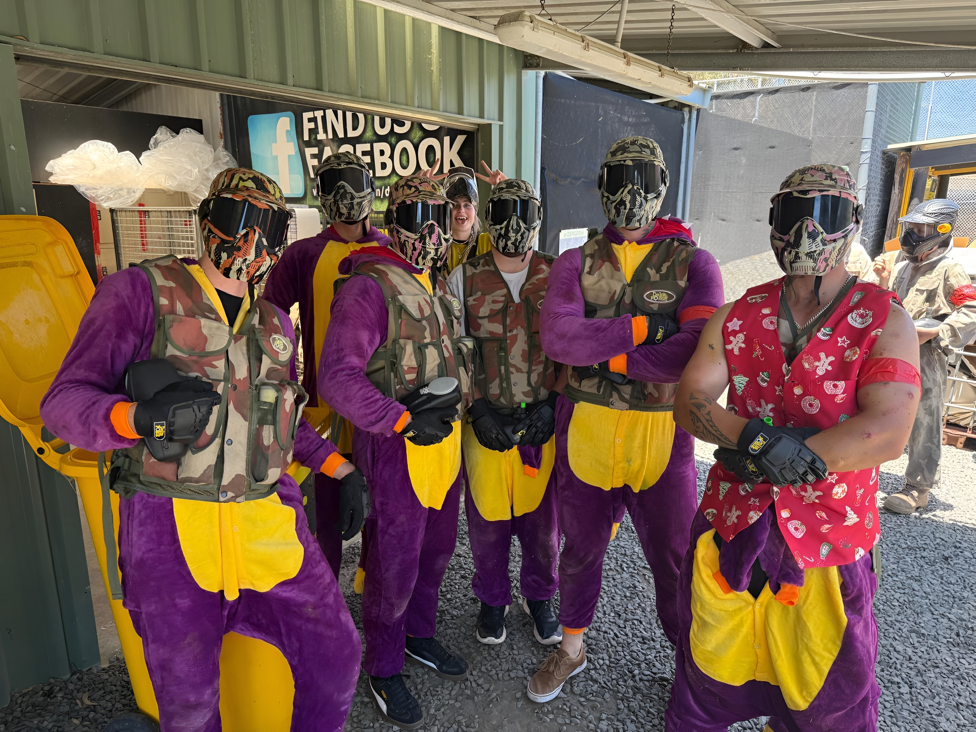 Stag party group in fancy dress and paintball masks at base camp