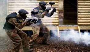 Two Paintball Players Advance on Hut Doorway