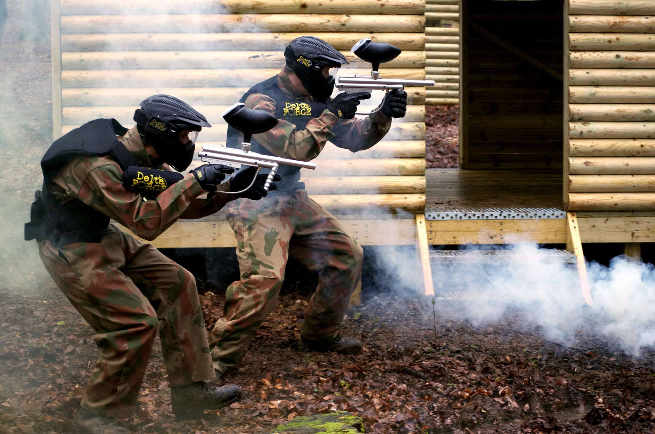 Two Paintball Players Advance on Hut Doorway