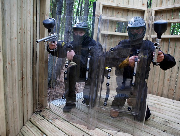 Two players crouch ready behind paintball shields