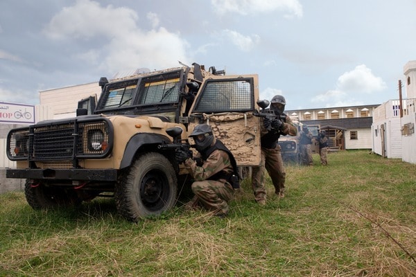 Paintball players take cover around armoured Jeep