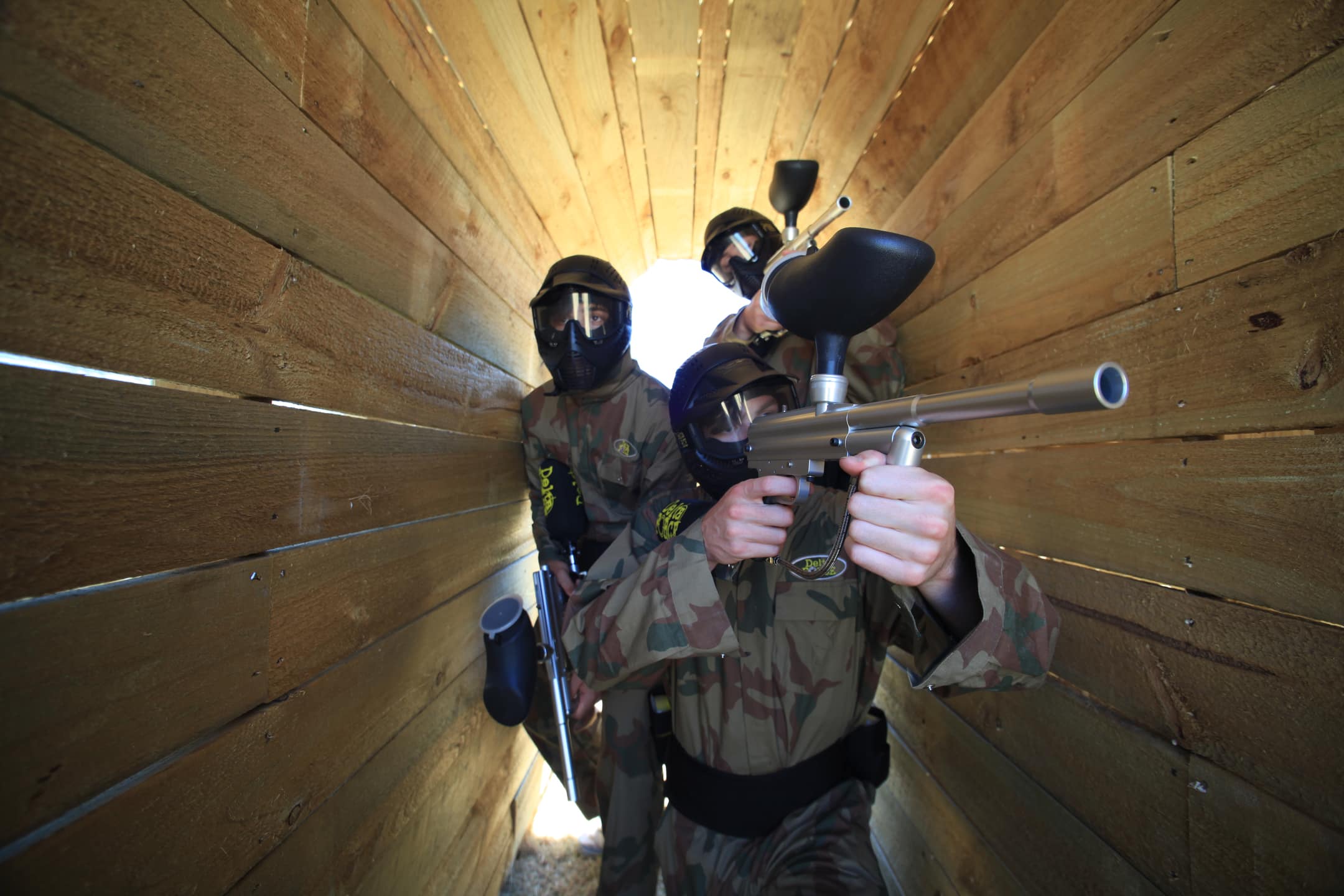 Three players advance through wooden tunnel