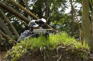 Reclining player takes aim from earth mound