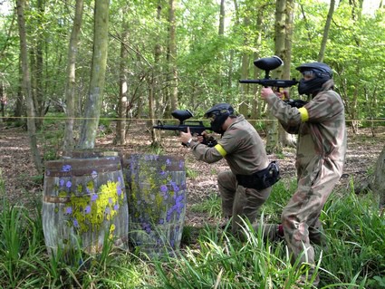 Two players fire M16s behind barrels