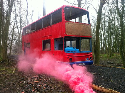 Red London double-decker bus engulfed in smoke