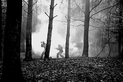 Players in the distance advance through smoke-ridden forest