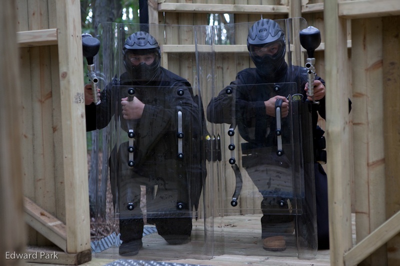 Two players crouch and aim behind riot shields