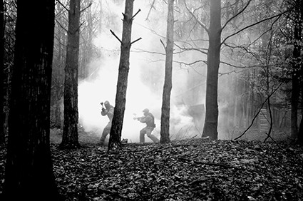 Players weave through trees and smoke in black and white