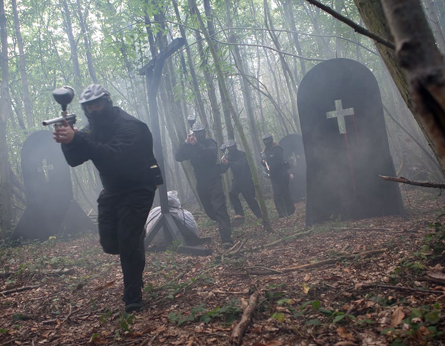 Squad of paintball players sprint through graveyard